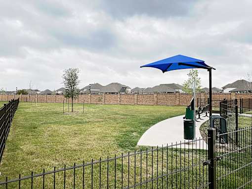 A blue umbrella is on a pole in a grassy area.