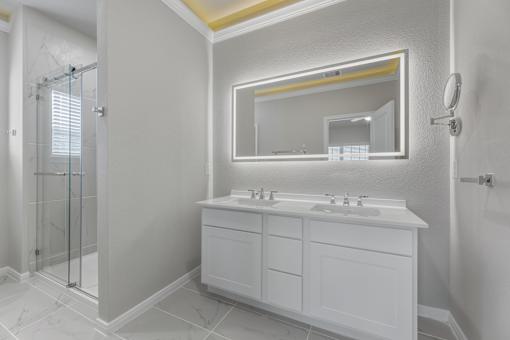 A white bathroom with a double sink vanity and a large mirror.