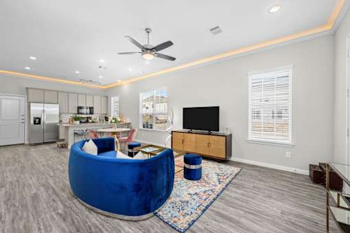 A blue velvet chair is in the middle of a living room.