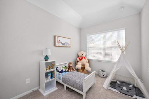 A child's bedroom with a white bed, a teepee, and a teddy bear.