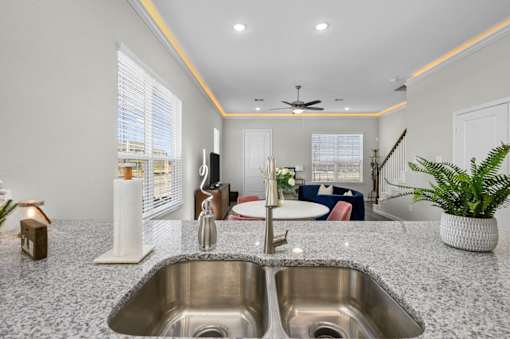 A modern kitchen with a double sink and a ceiling fan.