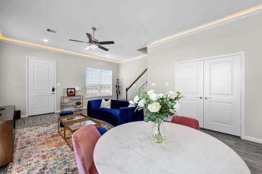 A living room with a white table and a vase of white flowers on it.