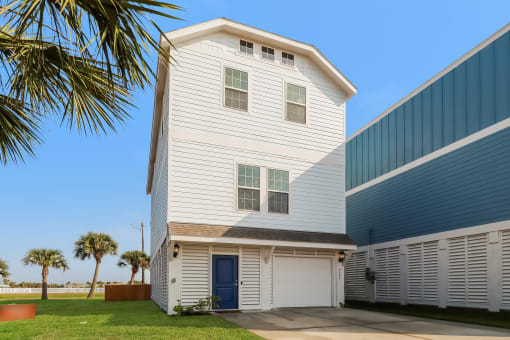 a white house with a blue door and a palm tree