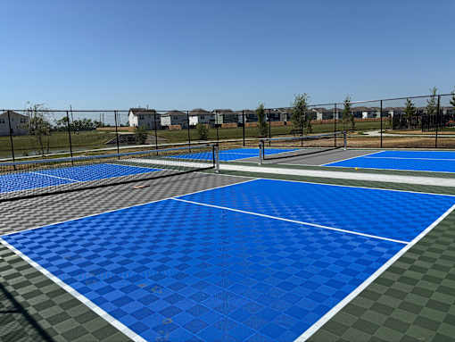 A blue and green checkered tennis court with a white line in the middle.