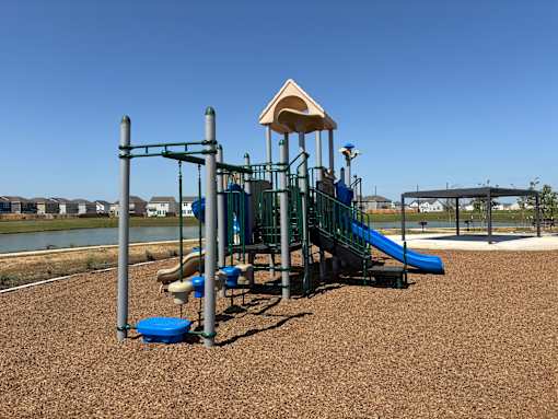 A playground with a blue slide and a brown sandy area.
