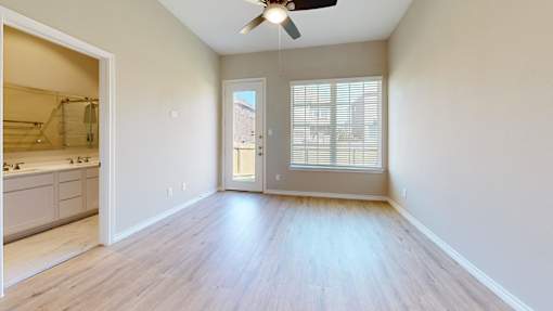 A room with a ceiling fan and a door leading to a balcony.