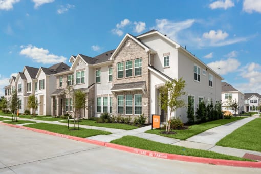 a row of town homes on a street with sidewalks and grass