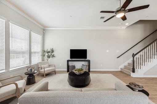 a living room with a couch and a tv in front of a staircase