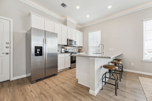 a large kitchen with stainless steel appliances and a bar with stools