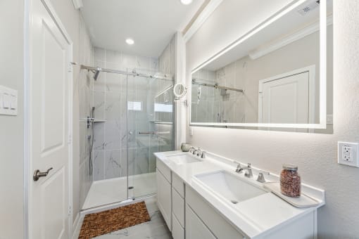 a white bathroom with a shower and a sink and a mirror