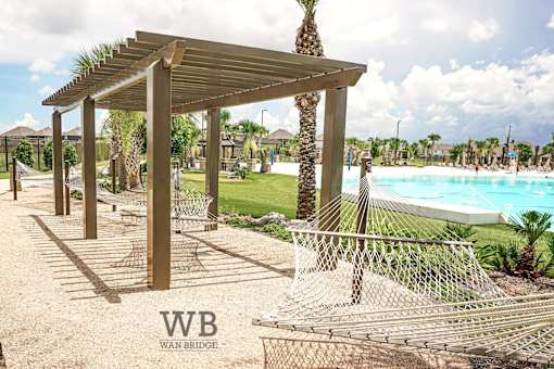 A pool area with a wooden pergola and a fence.