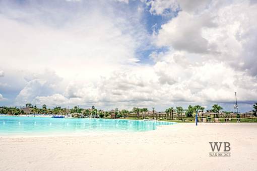A beach with a pool and palm trees.