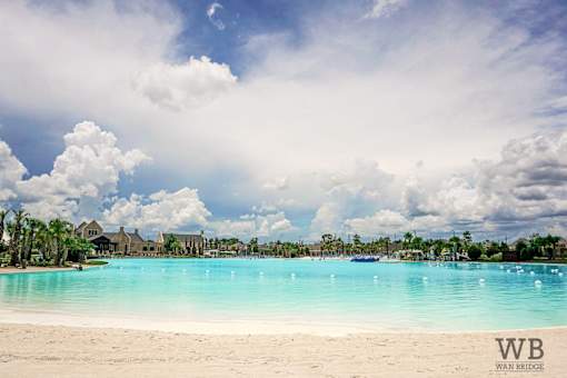 A beautiful beach with a clear blue sky and white clouds.
