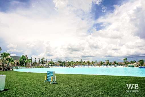 A large outdoor swimming pool with a blue tinted water and a white chair in the foreground.