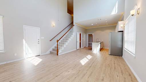 A spacious room with wooden floors and a staircase.