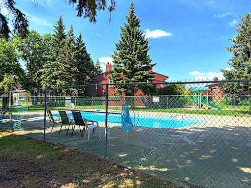 A pool surrounded by a fence with trees in the background.