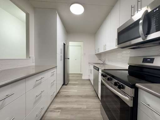 A modern kitchen with white cabinets and stainless steel appliances.