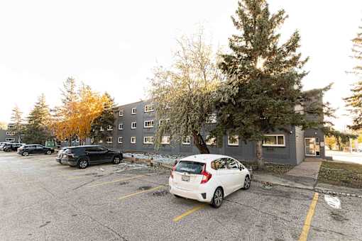 A parking lot with a white car parked in front of a grey building.