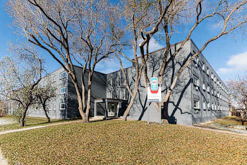 A grey building with a sign in front of it.
