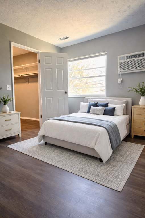 A bedroom with a bed, nightstand, and a window.