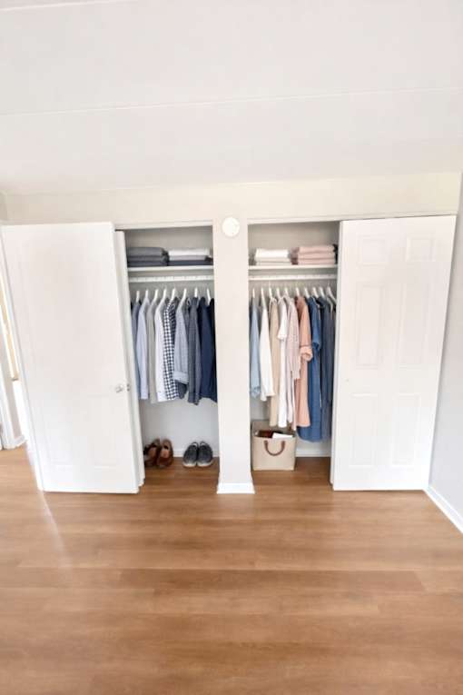 A white closet with clothes hanging inside.