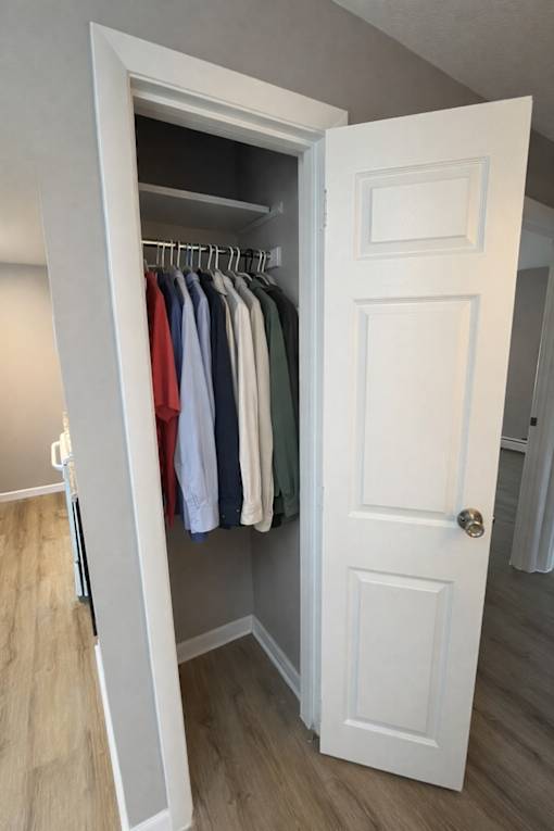 A white door is open to a closet with clothes hanging on it.