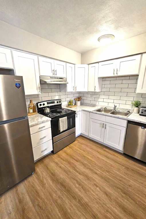 A kitchen with a stove, sink, and refrigerator.