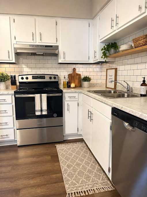 A modern kitchen with a stove, sink, and white cabinets.