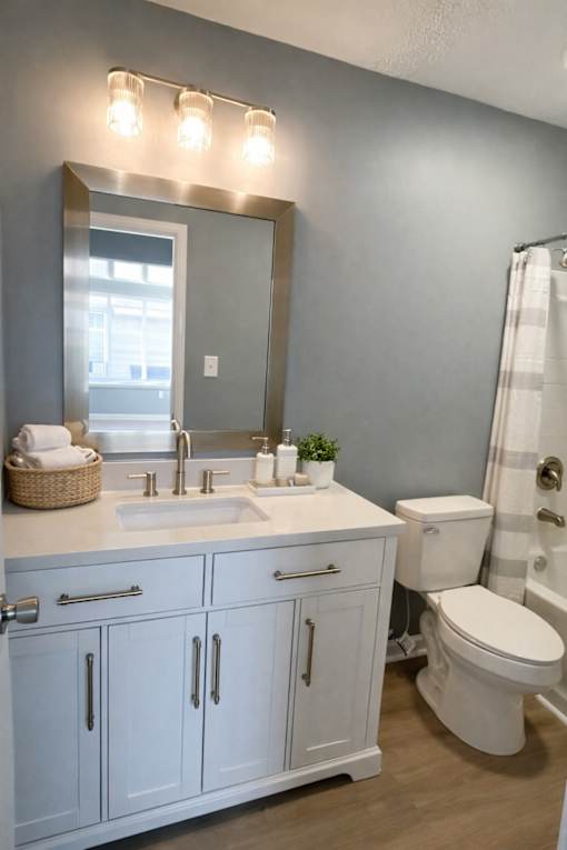 A bathroom with a white toilet, sink, and cabinets.