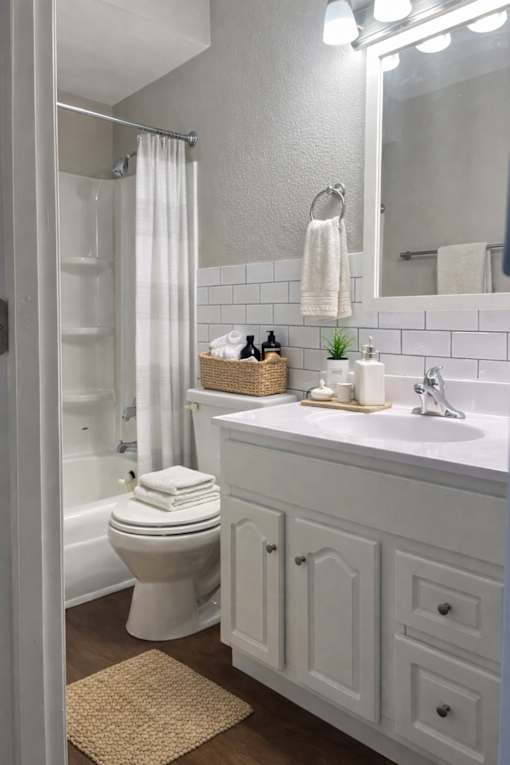 A white bathroom with a toilet, sink, and mirror.