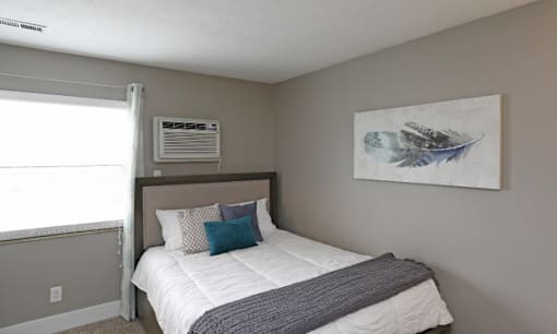 A bedroom with a bed, pillows, and a painting on the wall.