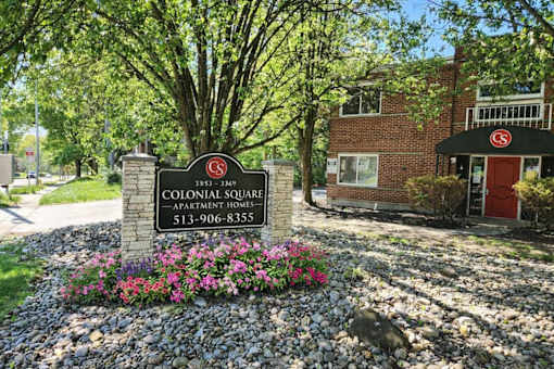 A sign for Colonial Square Apartment Homes is in front of a brick building.