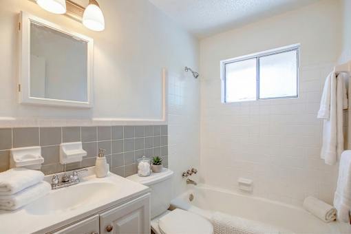 A white bathroom with a tub, sink, and mirror.
