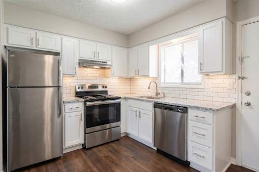 A kitchen with white cabinets and a stainless steel refrigerator.