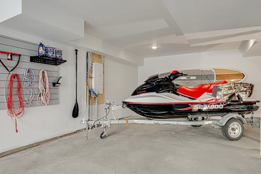 A red and black Sea-Doo jet ski is on a trailer in a garage.