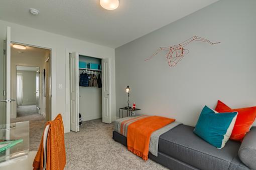 A bedroom with a bed, a chair, and a wall art of a spider.