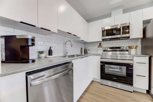 A modern kitchen with white cabinets and stainless steel appliances.