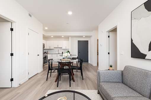 A modern living room with a dining table and grey couch.