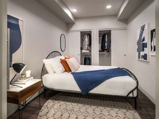 A bedroom with a bed, a nightstand, and a rug.