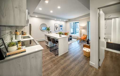 A modern kitchen with a white countertop and wooden flooring.