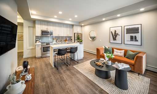 A modern living room with a kitchen in the background.