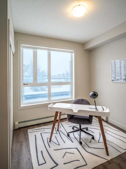 A room with a desk and chair in front of a large window.