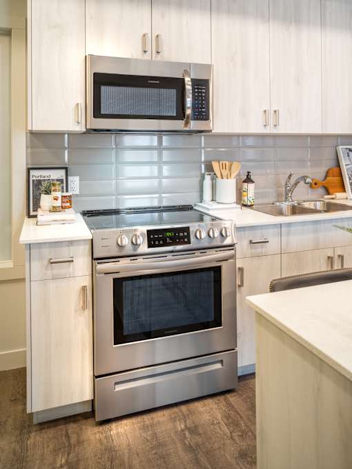 A modern kitchen with a stainless steel oven and microwave above it.