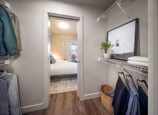 A bedroom with a bed, a mirror, and clothes hanging on a rack.