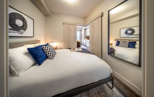 A bedroom with a large bed and a mirror on the wall.
