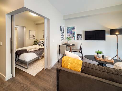 A bedroom with a bed, a couch, a chair, a table, and a lamp.