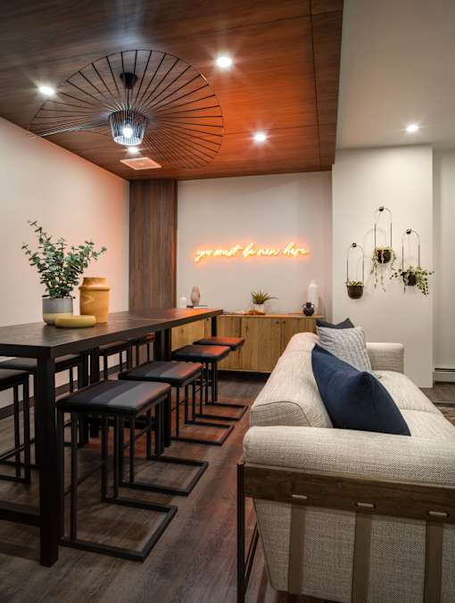 A room with a long table and a couch with a blue pillow.