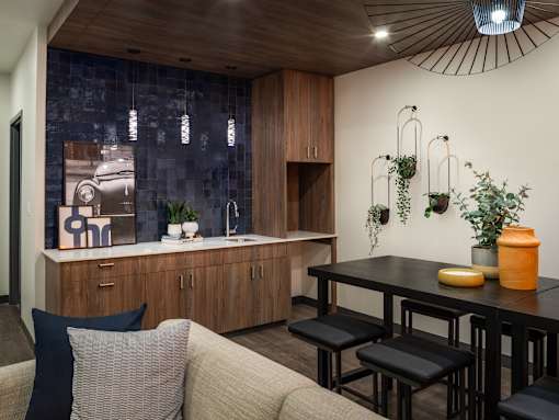 A modern kitchen with a wooden counter and a grey couch.