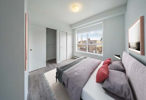A bedroom with a bed, pillows, and a window overlooking a cityscape.