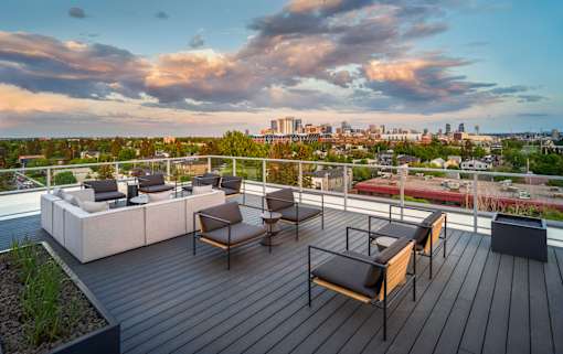 A wooden deck with a table and chairs overlooking a city skyline.